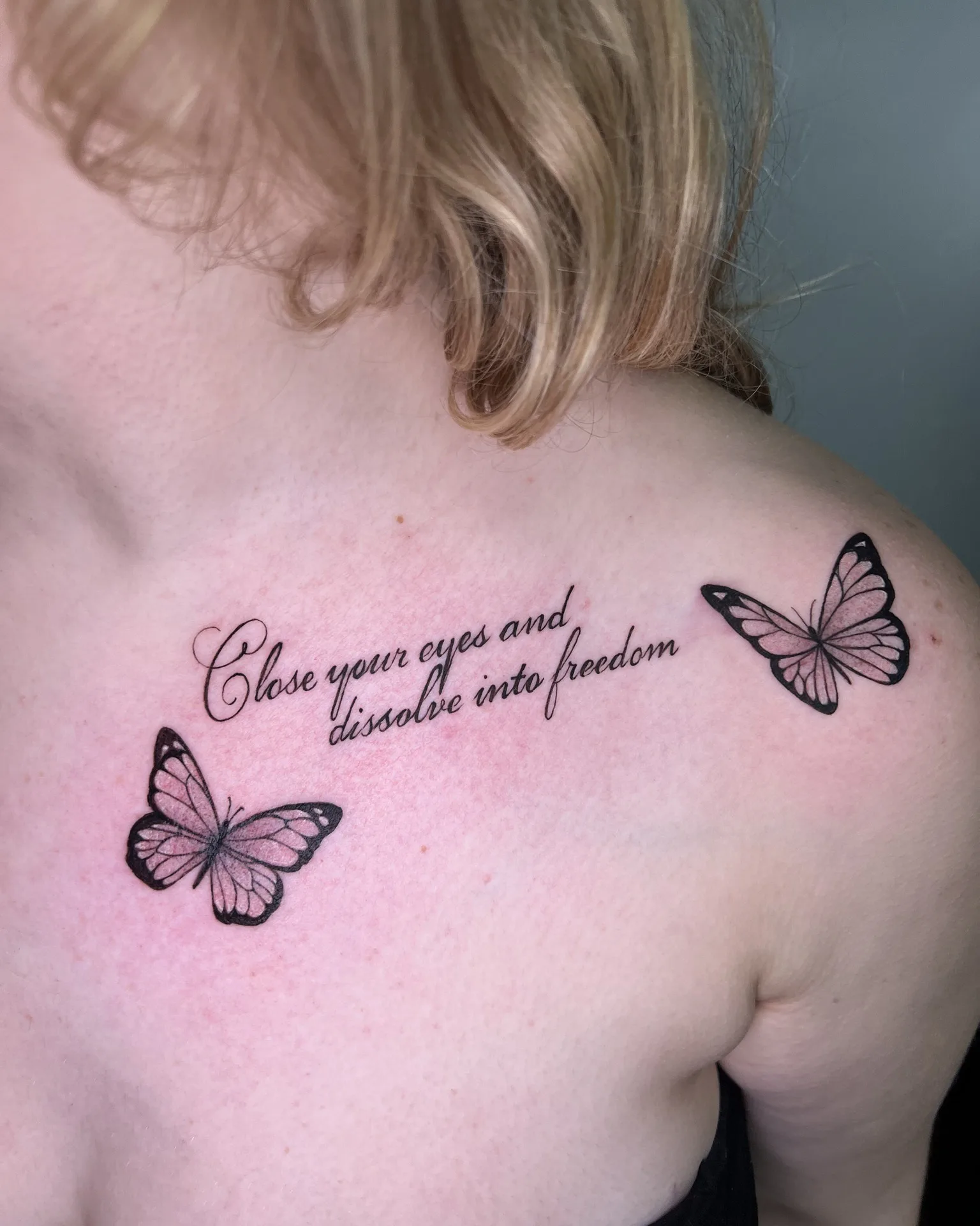 Две бабочки и надпись "Close your eyes and dissolve into freedom" на ключице.
